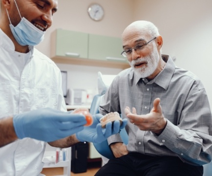 Dentist and patient looking at dental implant tooth replacement model